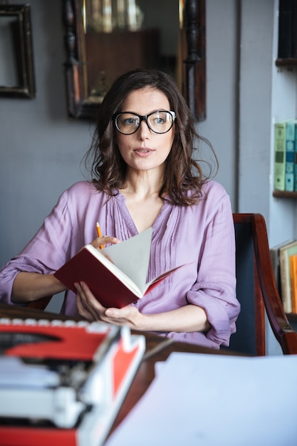 Portret van een doordachte volwassen vrouw in brillen bedrijf notebook