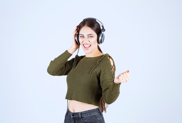 Portret van een expressief jong meisje dat naar muziek luistert en danst.