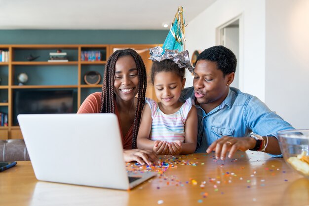 Portret van een familie die verjaardag online viert tijdens een videogesprek met laptop terwijl ze thuis blijft. Nieuw normaal levensstijlconcept.