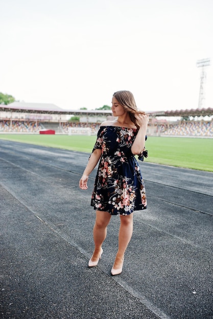 Portret van een fantastisch meisje in jurk en hoge hakken op de baan in het stadion