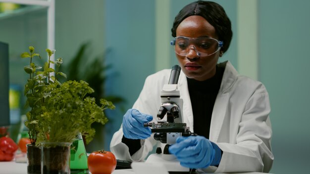 Portret van een farmaceutische vrouw die een glaasje onder de microscoop zet