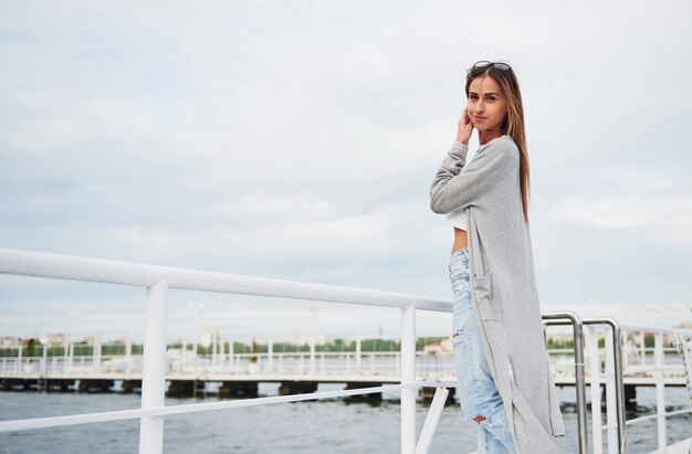 Portret van een gelukkig jong meisje in een stijlvolle jurk aan het water.