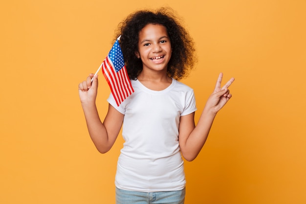 Portret van een gelukkig klein Afrikaans meisje dat Amerikaanse vlag houdt