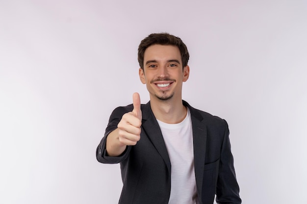 Portret van een gelukkig lachende jonge zakenman die duimen omhoog gebaar toont op geïsoleerde over witte achtergrond