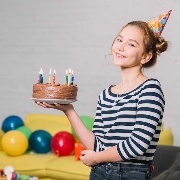 Portret van een gelukkig meisje die heerlijke cake op witte plaat in de partij houden