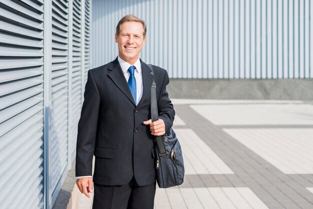 Portret van een gelukkig volwassen zakenman met handtas