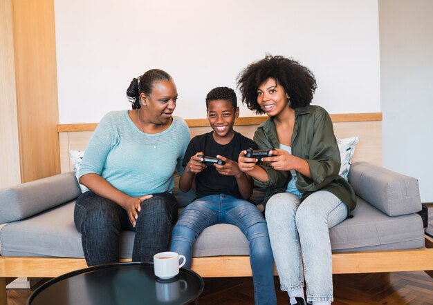 Portret van een gelukkige Afro-Amerikaanse familie die op de bank zit en consolevideogames speelt