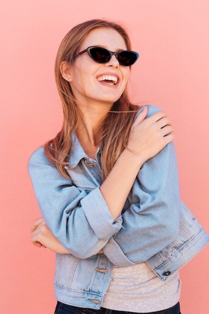 Portret van een gelukkige blonde jonge vrouw tegen roze achtergrond