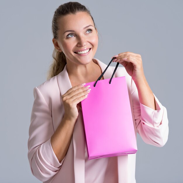 Portret van een gelukkige glimlachende vrouw met roze boodschappentas.