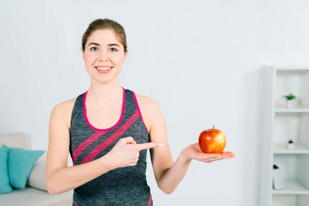 Portret van een gelukkige jonge fitness vrouw met rode appel in de hand