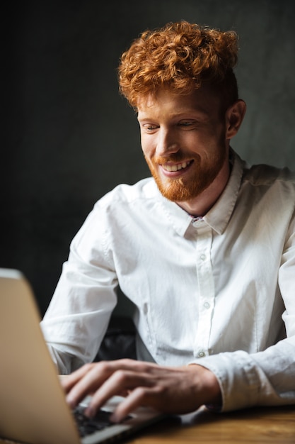 Portret van een gelukkige jonge man te typen op een laptop