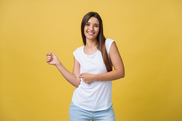 Portret van een gelukkige jonge vrouw die danst op gele achtergrond