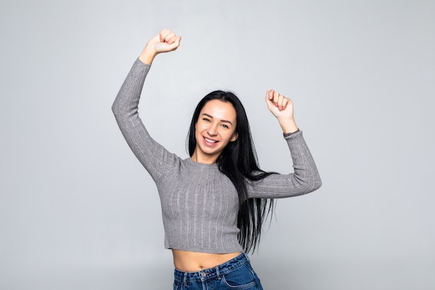 Portret van een gelukkige jonge vrouw die op grijze muur danst