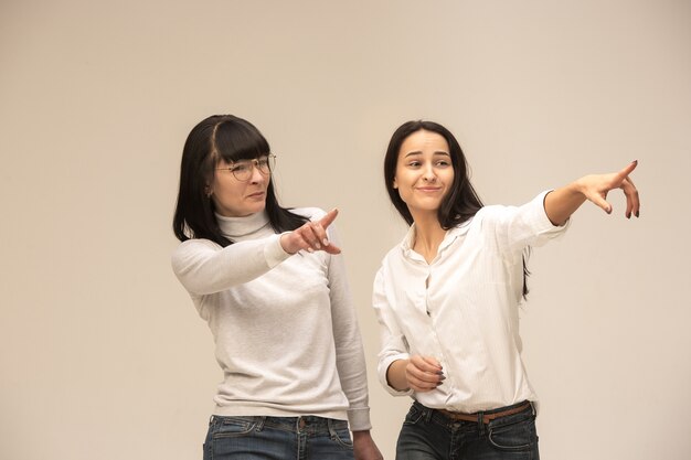 portret van een gelukkige moeder en dochter in de studio op een grijze achtergrond. Menselijke positieve emoties en gezichtsuitdrukkingen concept