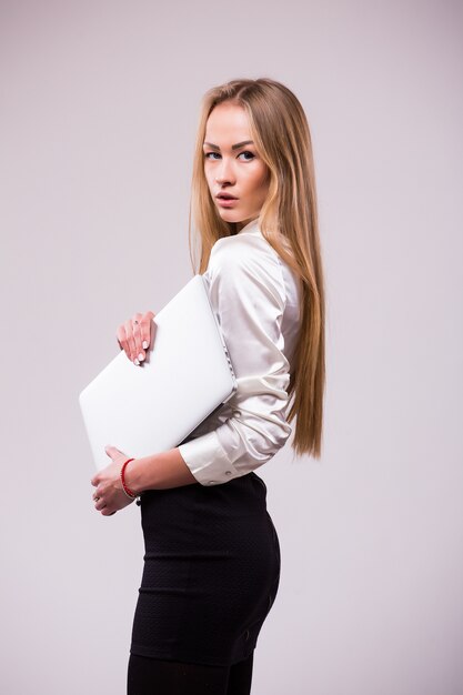 Portret van een gelukkige onderneemster die laptop computer houdt en weg kijkt die over witte muur wordt geïsoleerd