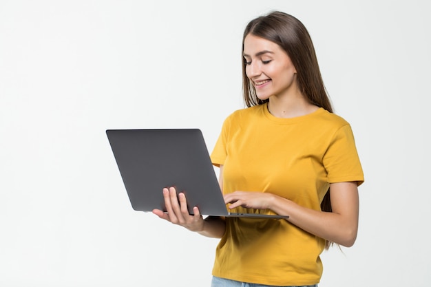 Portret van een gelukkige vrouw die aan laptop computer werkt die over witte muur wordt geïsoleerd