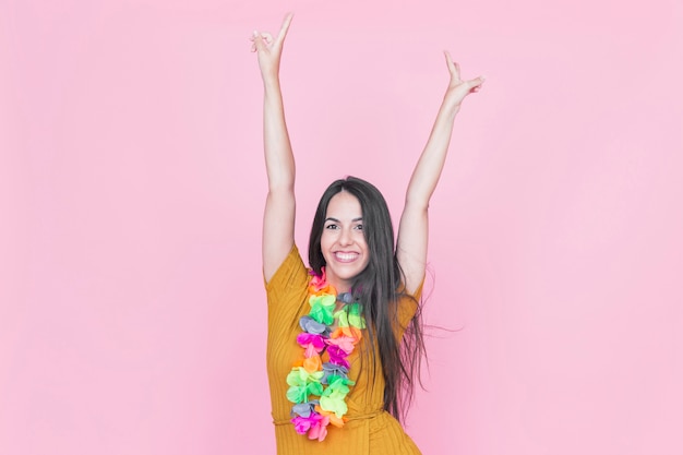 Portret van een gelukkige vrouw die haar wapens op roze achtergrond opheft