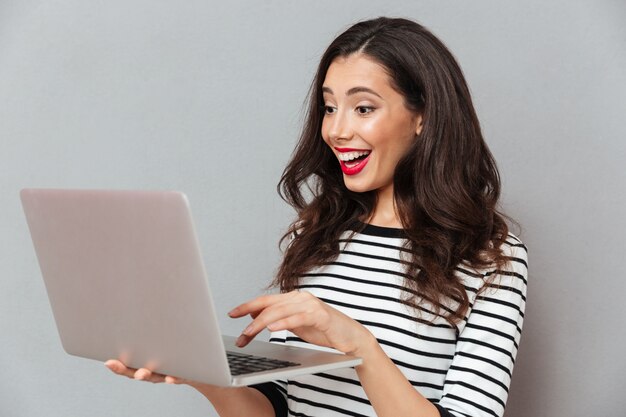 Portret van een gelukkige vrouw die laptop computer met behulp van