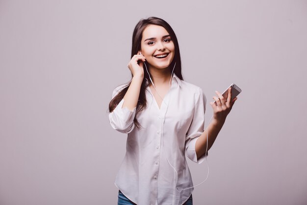 Portret van een gelukkige vrouw die muziek in hoofdtelefoons luistert die op een witte achtergrond wordt geïsoleerd