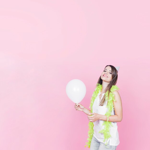 Portret van een gelukkige vrouw die witte ballon op roze achtergrond houdt