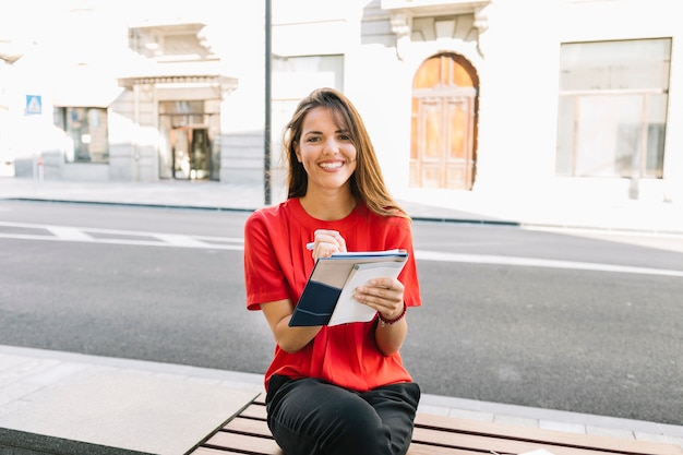 Gratis foto portret van een gelukkige vrouw het schrijven van notities in het dagboek