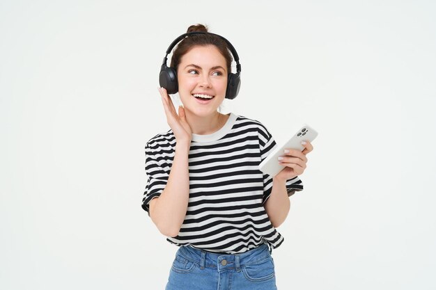 Portret van een gelukkige vrouw met een smartphone verandert liedje op mobiele telefoon streaming app luistert naar muziek in