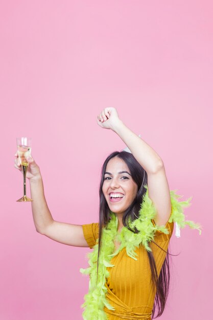 Portret van een gelukkige vrouw met wijnglas die op roze achtergrond dansen