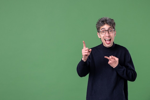 Portret van een geniale man, nonchalant gekleed in een studio-opname op een groene horizontale mannelijke schoolkleur