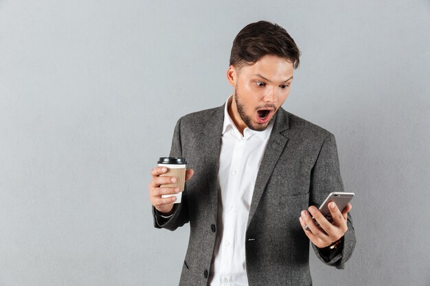 Portret van een geschokte zakenman die mobiele telefoon bekijkt