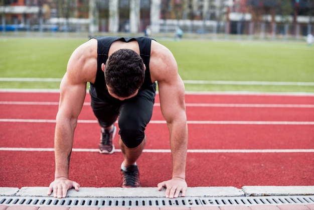 Gratis foto portret van een gezonde jonge man op track veld doet pushups