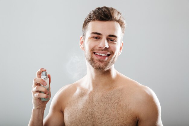 Portret van een glimlachend half naakt mensen bespuitend parfum