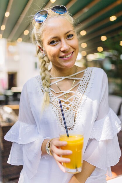 Portret van een glimlachend jong glas van de vrouwenholding sap met het drinken van stro daarin