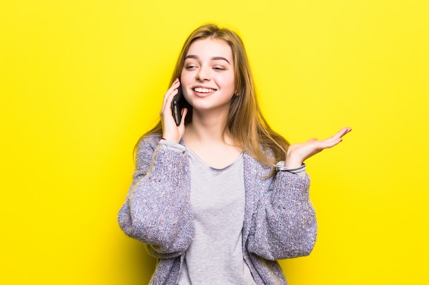 Portret van een glimlachend jong tienermeisje met steunen die op geïsoleerde mobiele telefoon spreken