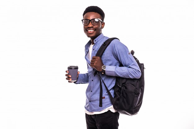 Portret van een glimlachende Afrikaanse Amerikaanse mannelijke student die met koffie lopen die op witte muur wordt geïsoleerd