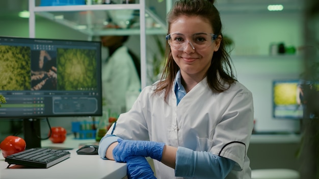 Portret van een glimlachende bioloogvrouw die genetisch gemodificeerd organisme analyseert