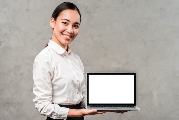 Portret van een glimlachende jonge aziatische zakenman die laptop met witte het schermvertoning toont