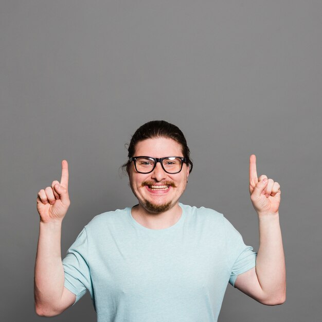 Portret van een glimlachende jonge mens die vingers richten die omhoog camera bekijken