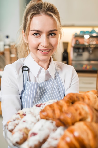 Portret van een glimlachende jonge vrouw die verse gebakken croissants houdt