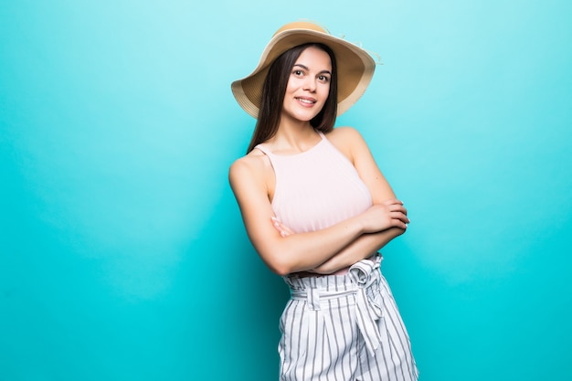 Portret van een glimlachende jonge vrouw die zich met gevouwen wapens bevindt en weg copyspace bekijkt die over blauwe muur wordt geïsoleerd.