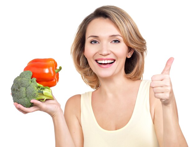 Portret van een glimlachende jonge vrouw met groenten die op wit wordt geïsoleerd.