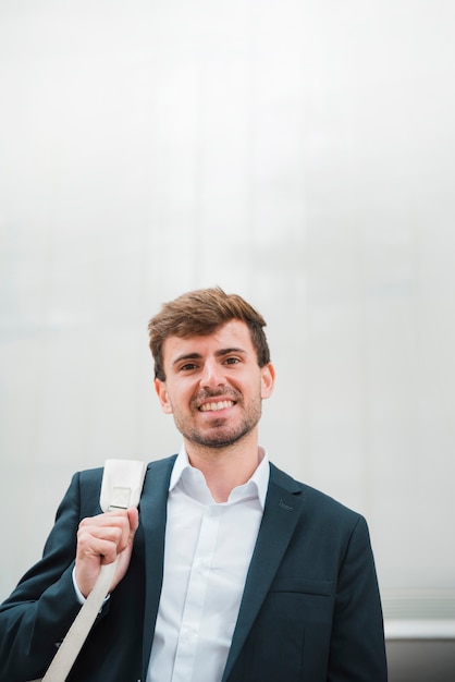 Portret van een glimlachende jonge zakenman tegen grijze muur