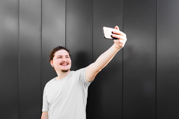 Portret van een glimlachende man die selfie op mobiele telefoon