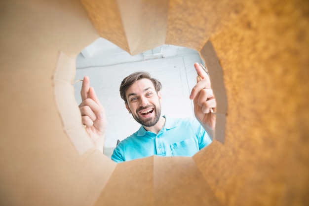 Gratis foto portret van een glimlachende man op zoek in papieren zak