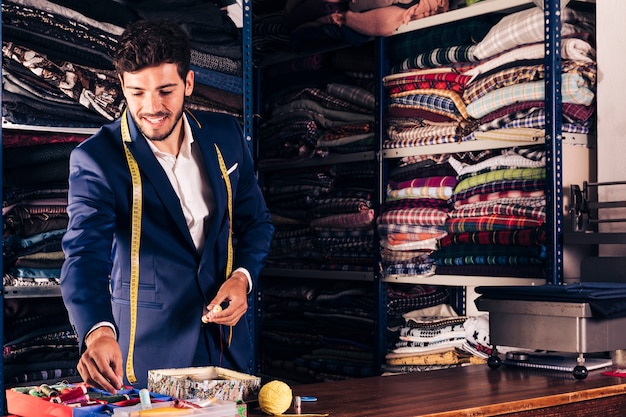 Gratis foto portret van een glimlachende mannelijke kleermaker die in zijn workshop werkt