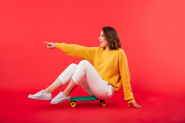 Portret van een glimlachende meisjeszitting op een skateboard