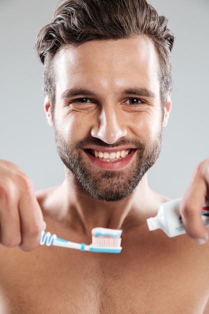 Portret van een glimlachende mens die tandpasta op een tandenborstel zet