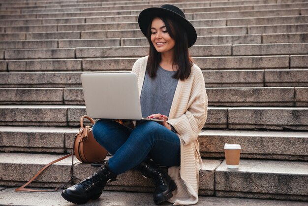 Portret van een glimlachende mooie vrouw die laptop computer met behulp van