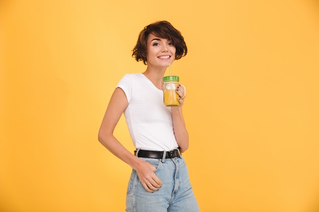 Portret van een glimlachende toevallige vrouw die sinaasappel drinkt
