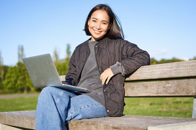 Portret van een glimlachende vrouw die met een laptop aan een project werkt of op afstand studeert en geniet van het zijn