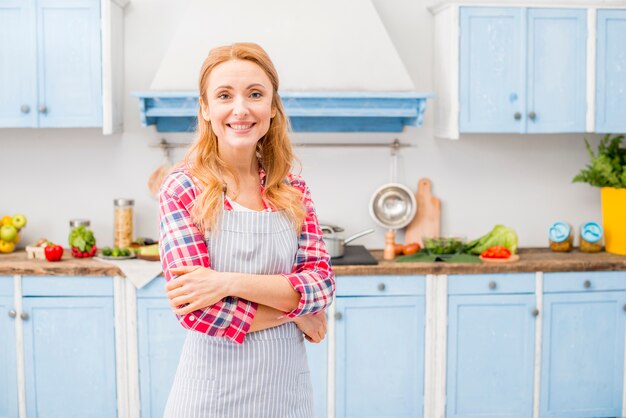 Portret van een glimlachende vrouw met haar gekruiste wapens het bekijken camera